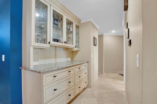 interior space featuring ornamental molding, cream cabinets, light tile patterned flooring, and light stone counters