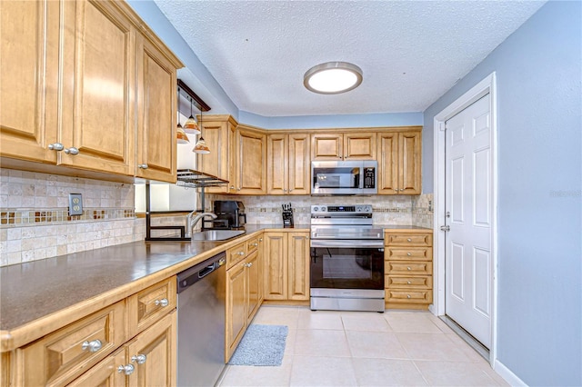 kitchen with decorative backsplash, light tile patterned floors, a textured ceiling, and stainless steel appliances