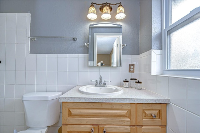 bathroom featuring vanity, tile walls, and toilet