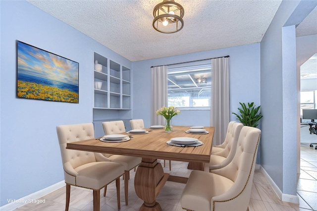 dining space with built in shelves, a wealth of natural light, and a textured ceiling