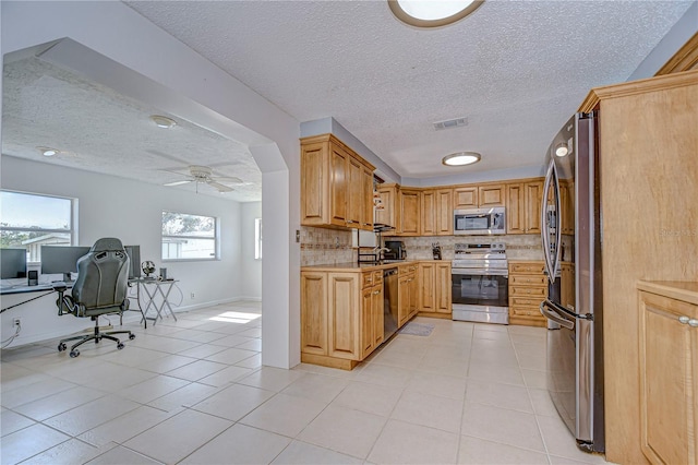 kitchen featuring ceiling fan, stainless steel appliances, tasteful backsplash, a textured ceiling, and light tile patterned flooring