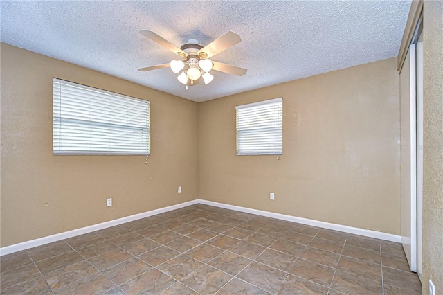 empty room with a textured ceiling, dark tile patterned floors, and ceiling fan