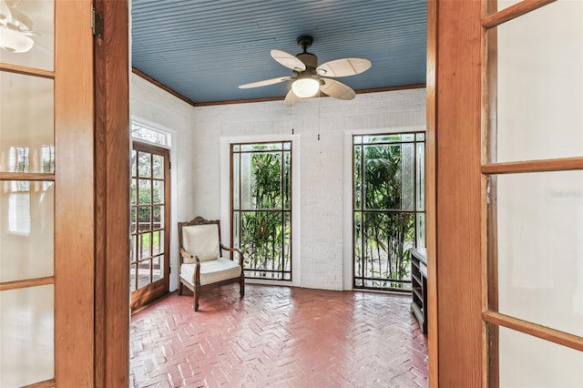 sitting room with brick floor, ceiling fan, and ornamental molding