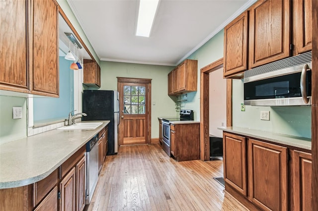 kitchen with stainless steel appliances, a sink, light countertops, light wood finished floors, and brown cabinetry