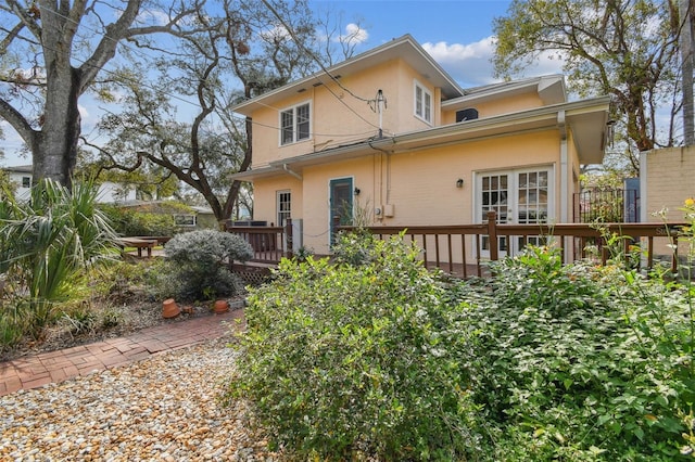 back of house featuring french doors, a deck, and stucco siding