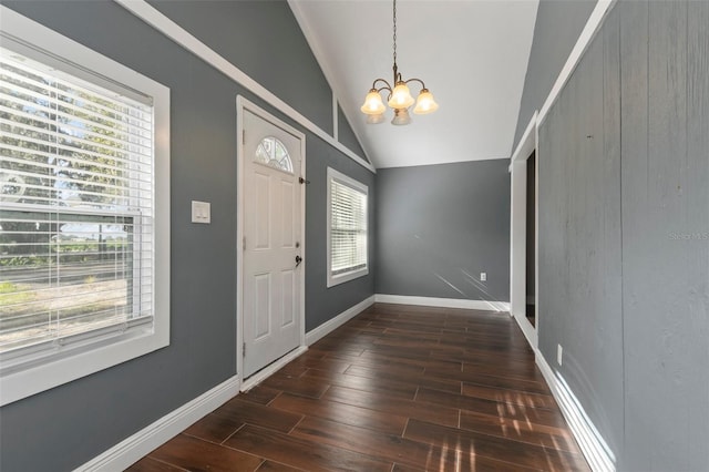 entryway featuring dark hardwood / wood-style flooring, lofted ceiling, and a chandelier