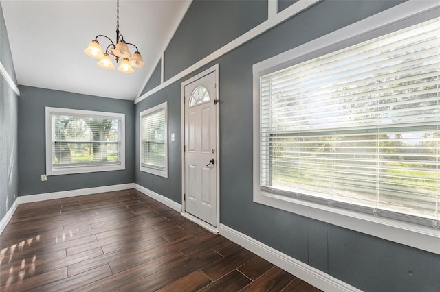 entrance foyer featuring dark hardwood / wood-style flooring, an inviting chandelier, vaulted ceiling, and a wealth of natural light