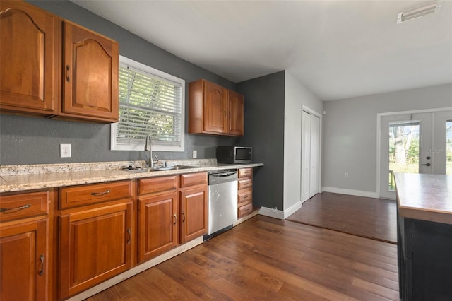 kitchen with light stone countertops, appliances with stainless steel finishes, dark hardwood / wood-style flooring, french doors, and sink