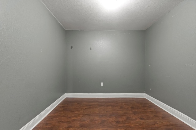 unfurnished room with dark hardwood / wood-style flooring and a textured ceiling