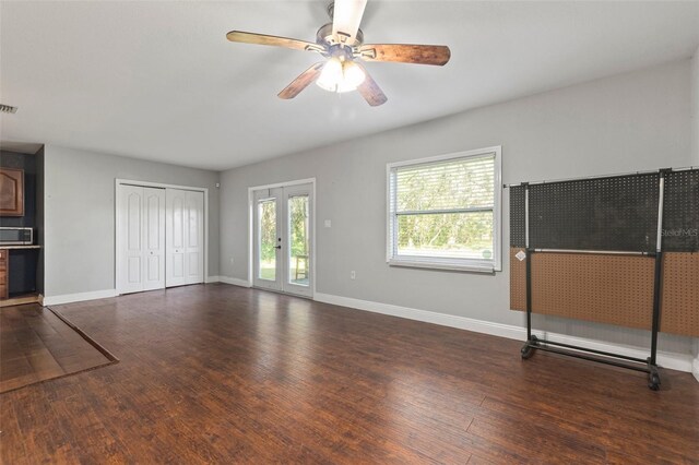 unfurnished living room with ceiling fan, french doors, and dark hardwood / wood-style floors