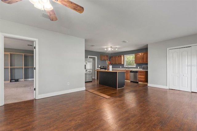 kitchen featuring appliances with stainless steel finishes, dark hardwood / wood-style flooring, ceiling fan, sink, and a center island