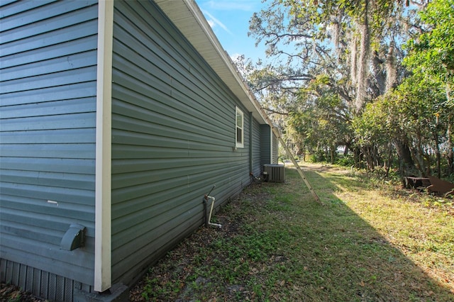 view of side of property with central air condition unit and a yard