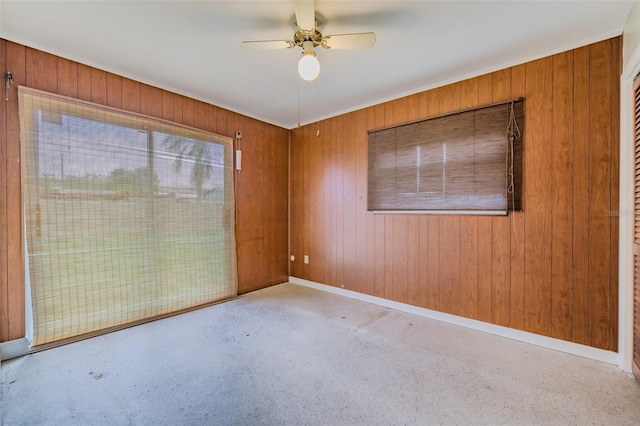 unfurnished room with ceiling fan and wooden walls