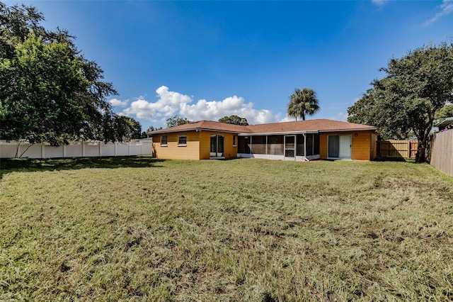 rear view of house featuring a sunroom and a yard