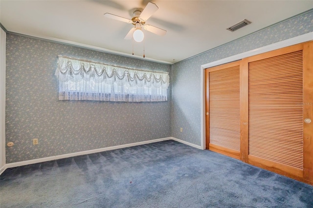 unfurnished bedroom with ceiling fan, a closet, ornamental molding, and dark colored carpet