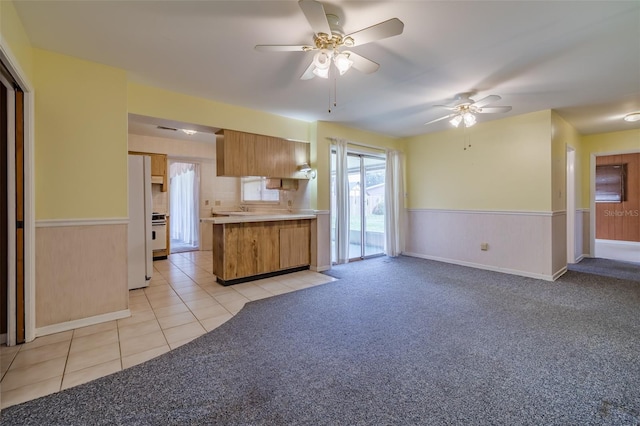 kitchen with kitchen peninsula, ceiling fan, light tile patterned flooring, and white fridge