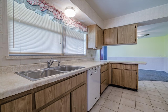 kitchen with kitchen peninsula, tasteful backsplash, sink, light tile patterned floors, and dishwasher