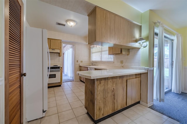 kitchen featuring white appliances, sink, light tile patterned floors, tasteful backsplash, and kitchen peninsula