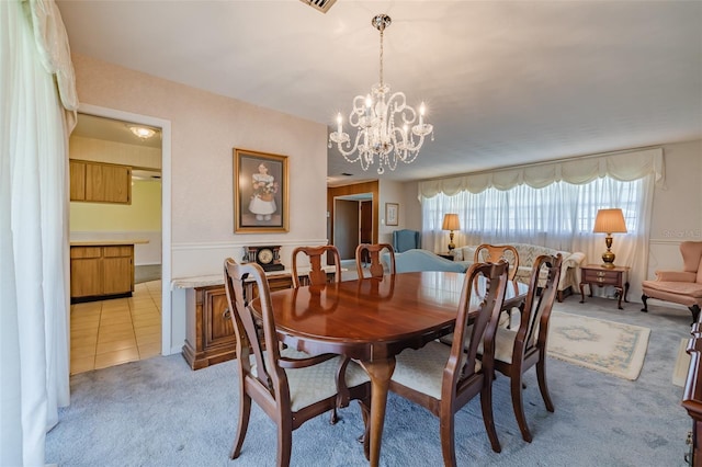 dining room featuring light colored carpet and an inviting chandelier