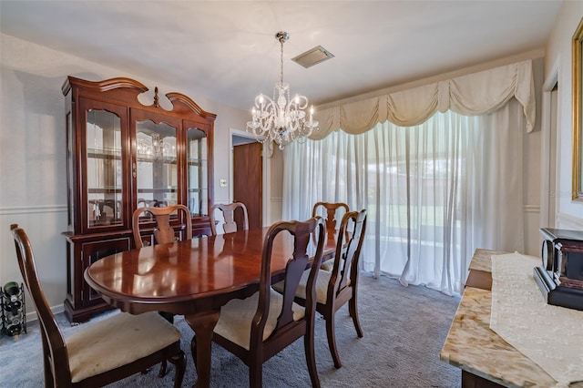 dining room with carpet and a notable chandelier