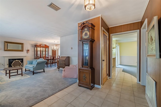 corridor with light colored carpet, an inviting chandelier, ornamental molding, and wood walls