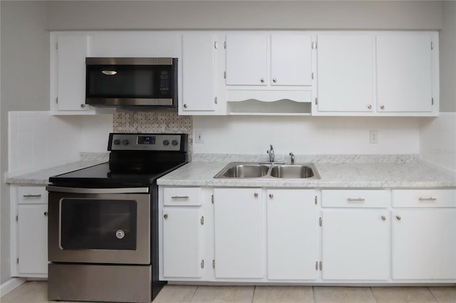 kitchen with white cabinets, appliances with stainless steel finishes, light tile patterned floors, and sink