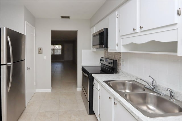 kitchen with sink, stainless steel appliances, light tile patterned floors, backsplash, and white cabinets