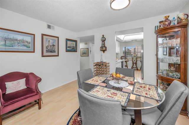 dining area featuring visible vents, a textured ceiling, and wood finished floors