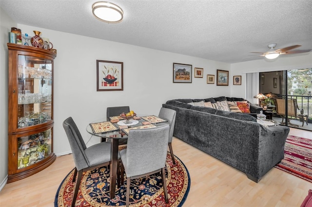 dining space featuring light wood-style floors, a ceiling fan, and a textured ceiling