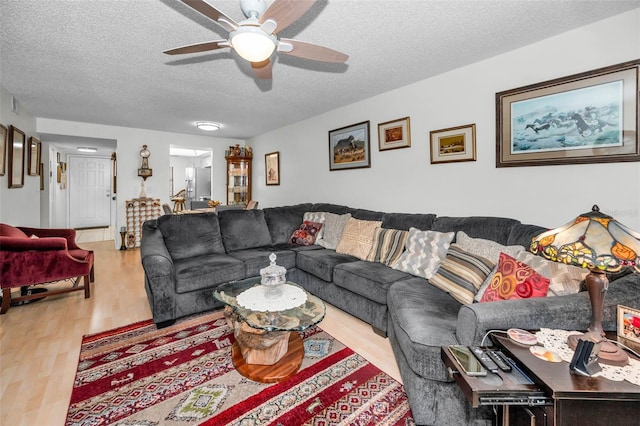 living area with a textured ceiling, wood finished floors, and a ceiling fan