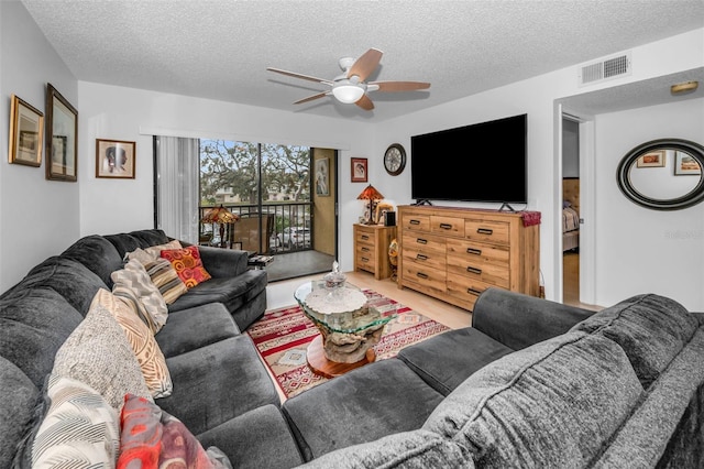 living area with a textured ceiling, visible vents, and a ceiling fan