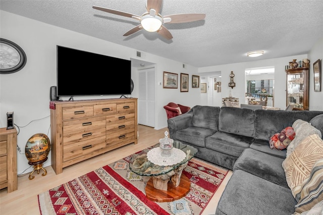 living area with visible vents, a textured ceiling, light wood-style flooring, and a ceiling fan