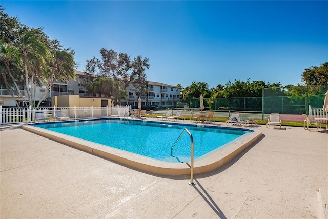 pool with a patio area and fence