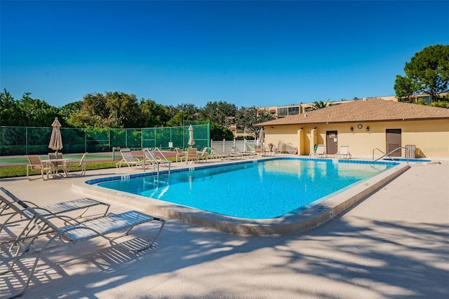 pool with a patio area and fence