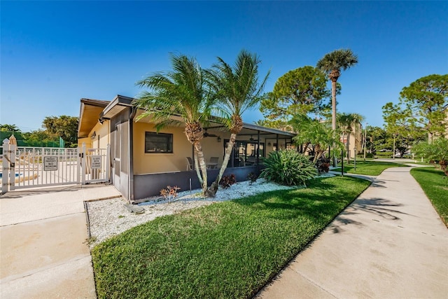 view of property exterior with a lawn, fence, a gate, and stucco siding