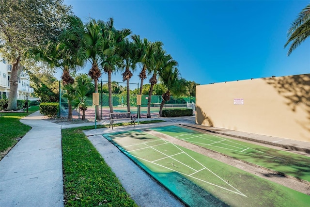 view of property's community with fence and shuffleboard