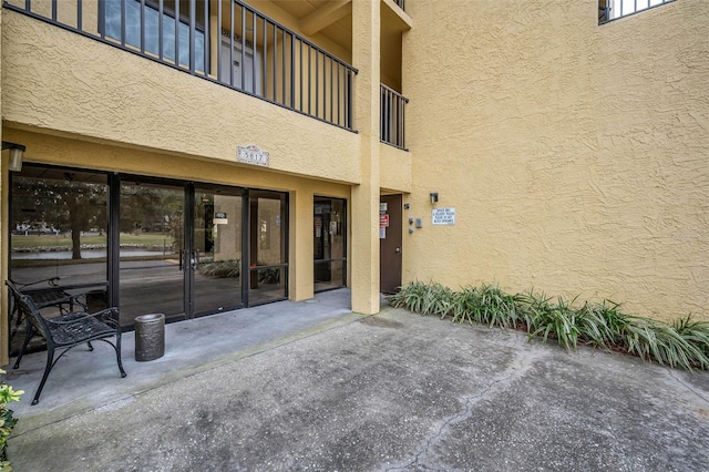 entrance to property featuring a patio and stucco siding