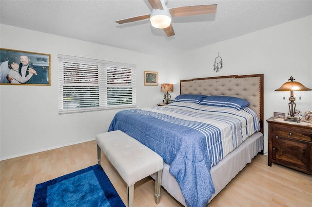 bedroom featuring a ceiling fan, a textured ceiling, baseboards, and wood finished floors