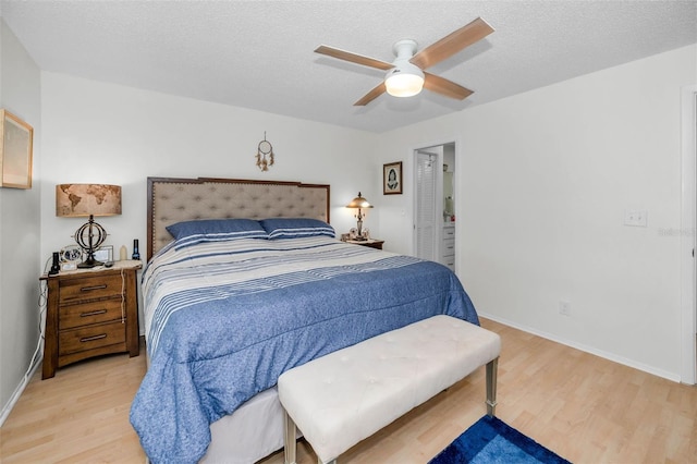 bedroom featuring a ceiling fan, baseboards, a textured ceiling, and light wood finished floors