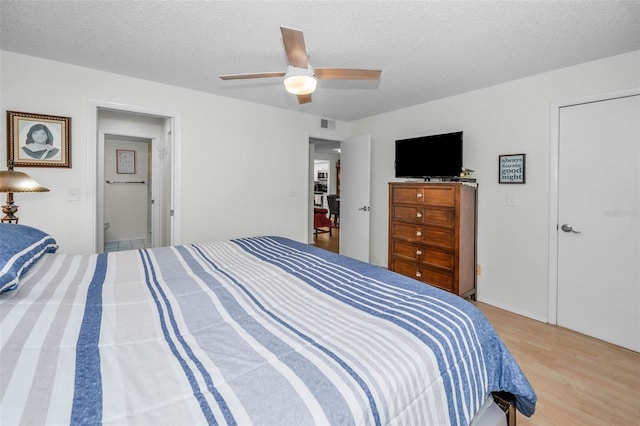 bedroom featuring a textured ceiling, ceiling fan, wood finished floors, and visible vents