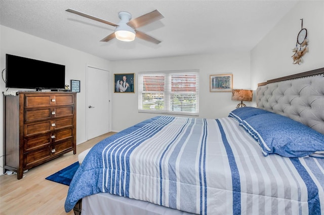 bedroom with light wood-style floors, ceiling fan, and a textured ceiling