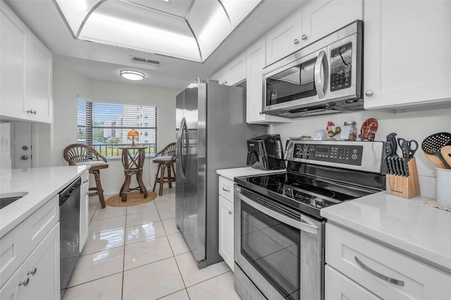 kitchen with light tile patterned floors, visible vents, appliances with stainless steel finishes, white cabinets, and light stone countertops