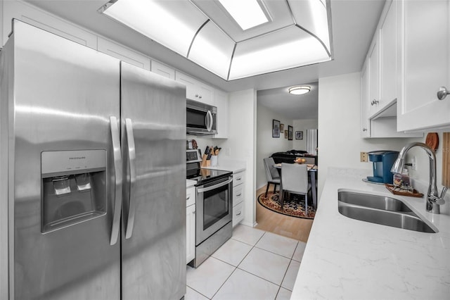 kitchen featuring stainless steel appliances, white cabinetry, a sink, and light tile patterned floors