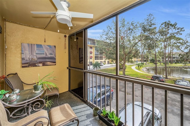 balcony with a ceiling fan, a sunroom, and a water view