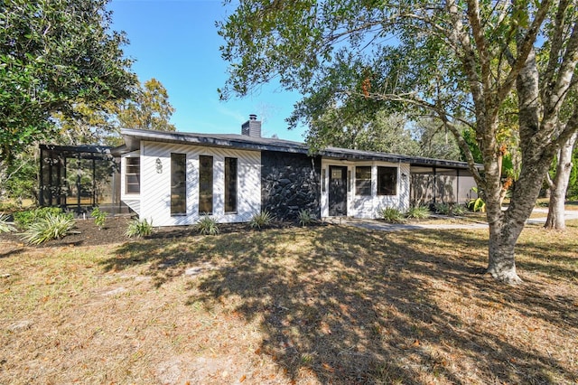 view of front of home with a front yard and a sunroom