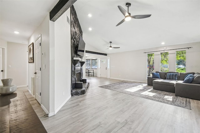 living room with a stone fireplace, ceiling fan, lofted ceiling, and light wood-type flooring