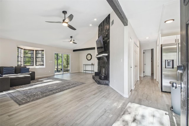 living room featuring ceiling fan, a stone fireplace, light wood-type flooring, and lofted ceiling