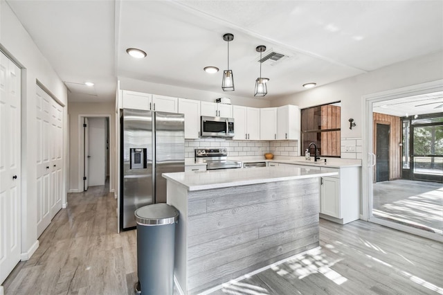 kitchen featuring appliances with stainless steel finishes, light hardwood / wood-style flooring, white cabinetry, and sink