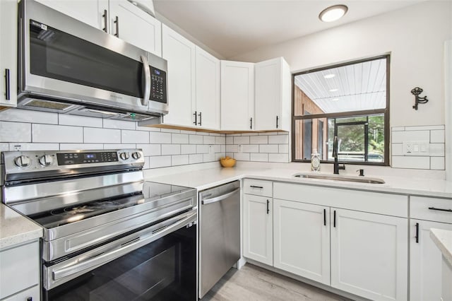 kitchen with white cabinets, sink, light hardwood / wood-style flooring, light stone counters, and stainless steel appliances