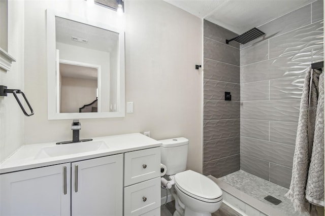 bathroom featuring tiled shower, vanity, and toilet